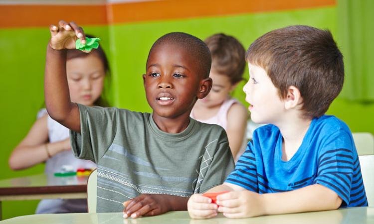 children-teaser-image-1 Children playing together, sat at desks